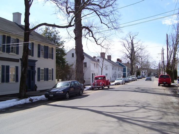 cars parked on the side of a street in front of houses with snow on the ground