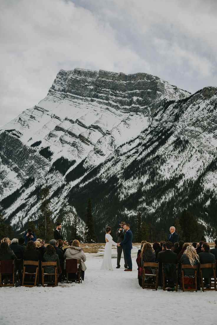 a couple getting married in front of snowy mountains