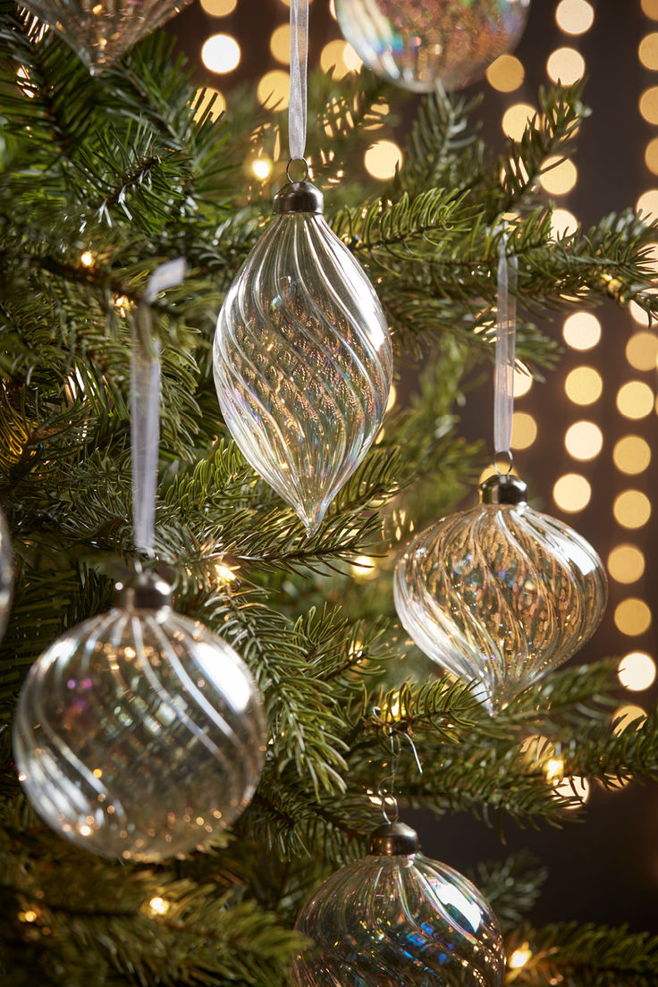 christmas ornaments hanging from a tree with lights in the background