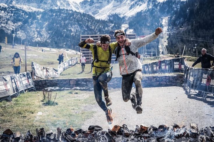 two men running down a dirt road with their arms in the air