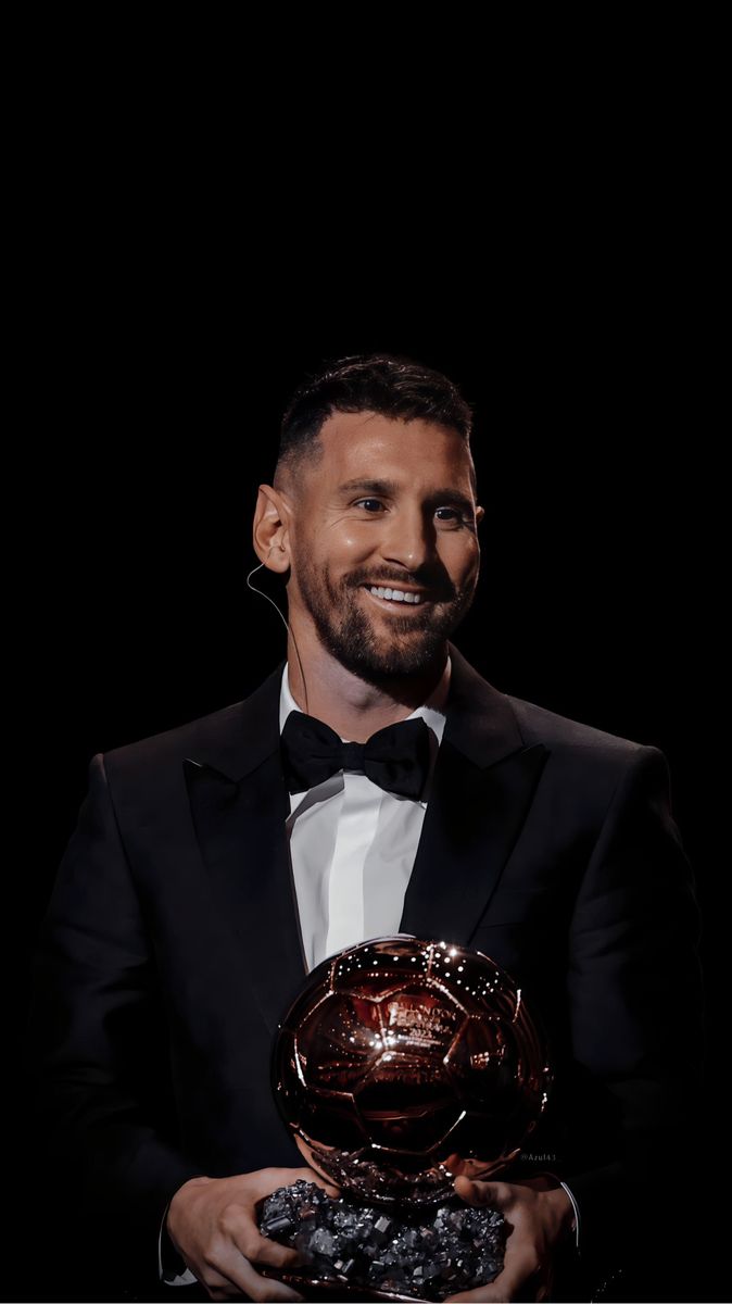 a man in a tuxedo holding an award for best football player at the ballon d'or