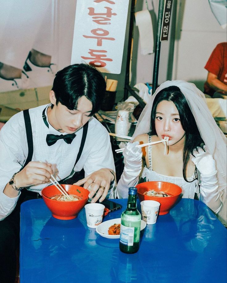 a man and woman sitting at a table with bowls of food in front of them