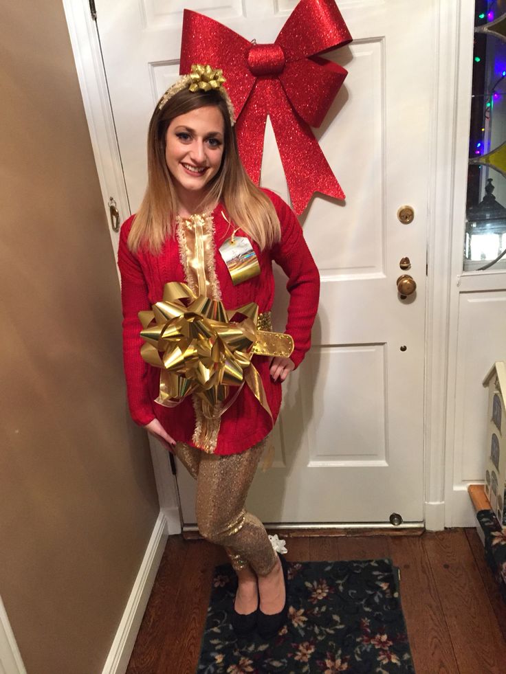 a woman standing in front of a door wearing a red sweater and gold leggings