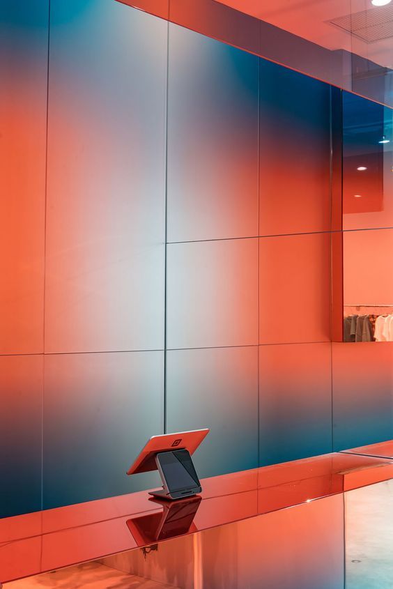 a laptop computer sitting on top of a glass table in front of a colorful wall