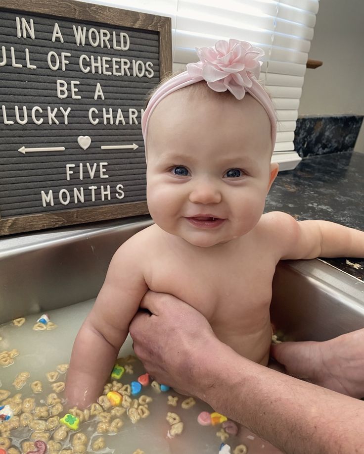 a baby sitting in a sink next to a sign