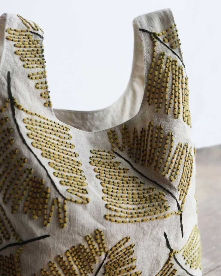 a white bag with yellow leaves on it sitting on top of a wooden table next to a wall