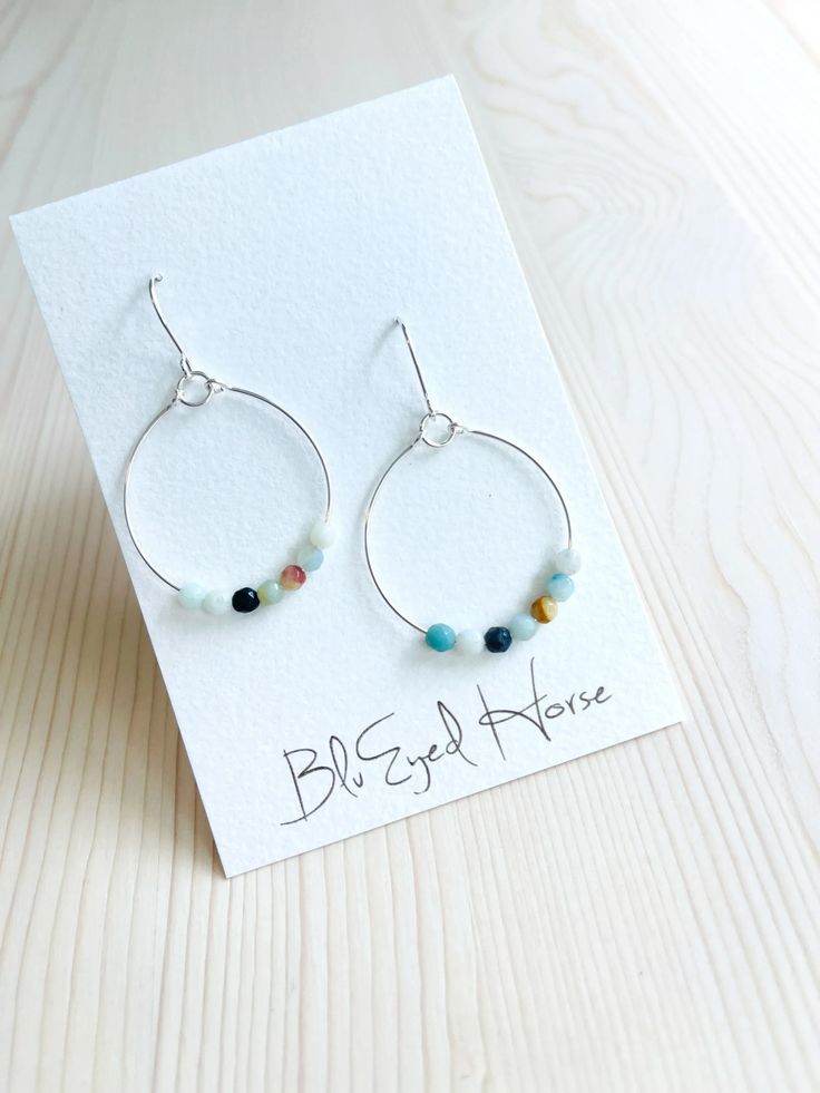 Discover the charm of Zena Earrings, featuring stunning amazonite gemstone beads encased in beautiful silver round hoops. These eye-catching earrings will add a touch of elegance to any outfit, making you the center of attention wherever you go. Don't miss out on this unique and stylish accessory – click here to see more! Coastal Jewelry, Classic Metal, Colorful Earrings, Colorful Jewelry, Stylish Accessories, Boho Jewelry, Boho Outfits, Gemstone Beads, Jewelry Pieces