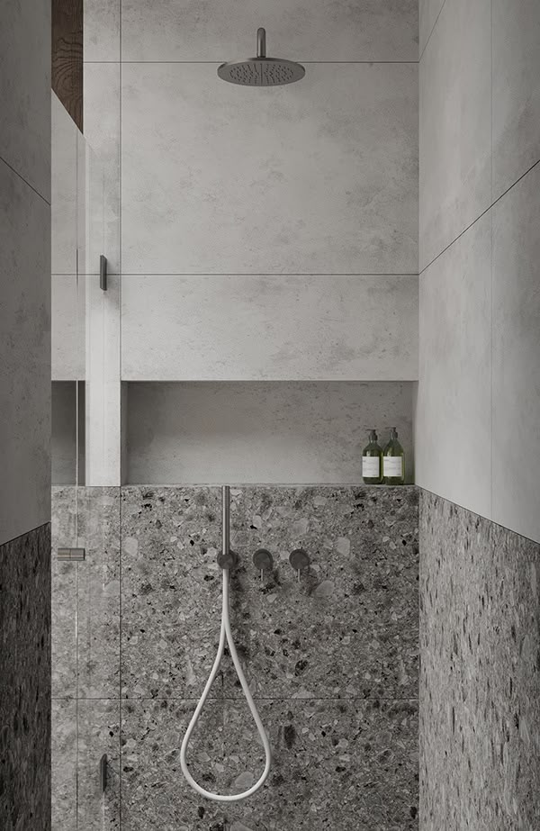 a shower head in the corner of a bathroom with stone walls and flooring,