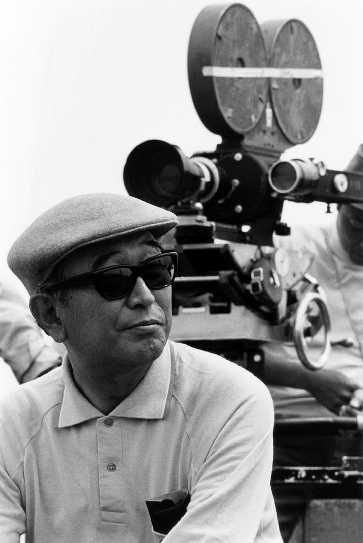 black and white photograph of two men sitting in front of a movie camera, one with sunglasses on his head