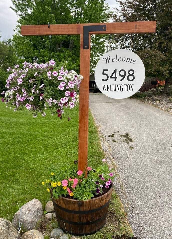 a welcome sign in front of a wooden barrel with flowers growing out of the bottom