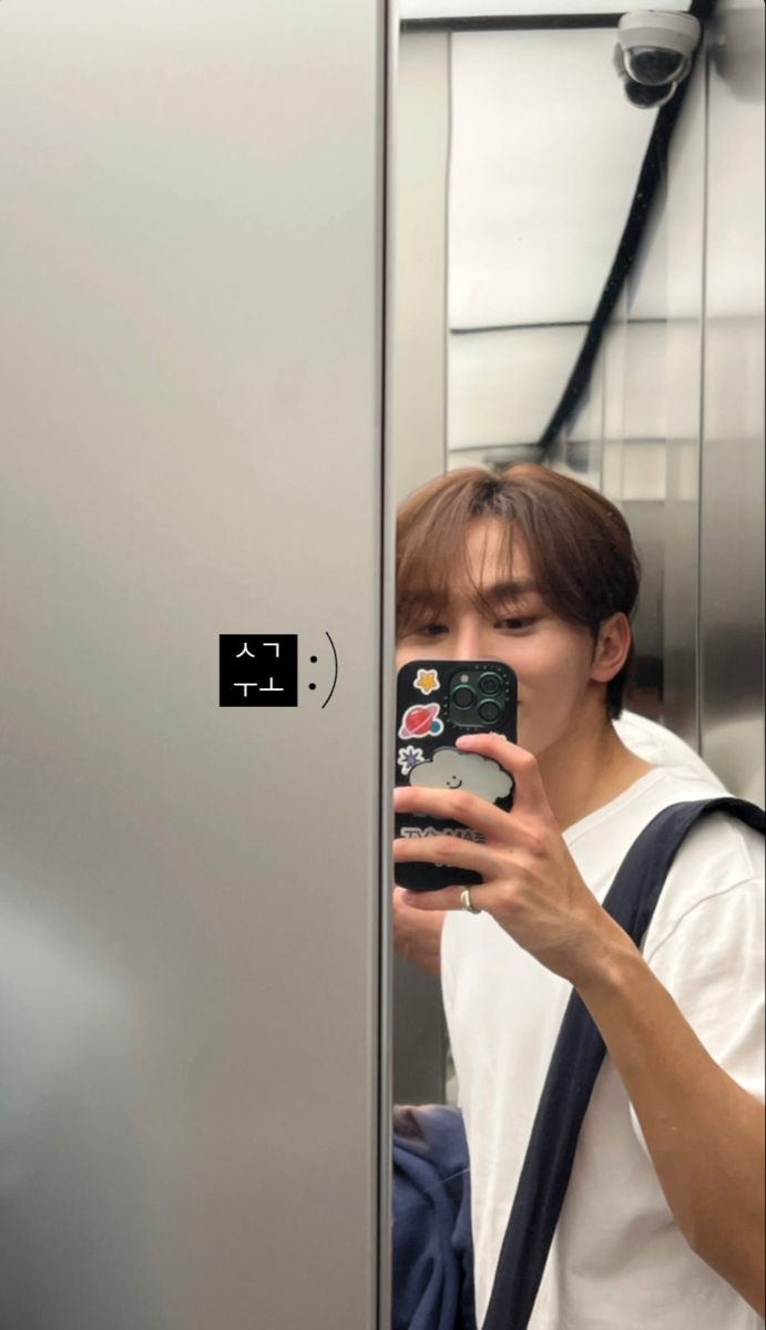 a young man taking a selfie in an elevator with his cell phone up to his ear