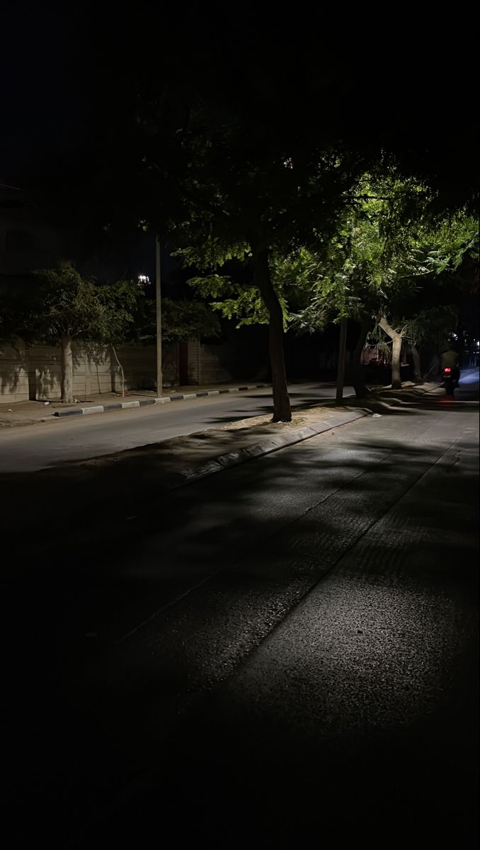 an empty street at night with no one on the sidewalk or cars parked along it