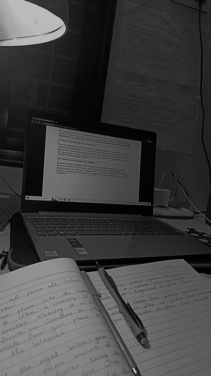 an open notebook sitting on top of a desk next to a laptop computer and lamp