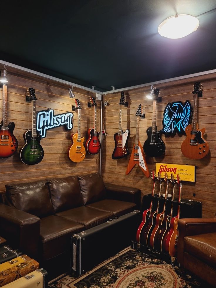 guitars are hanging on the wall in a music room with leather couches and rugs