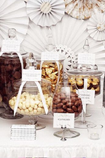 a table topped with lots of different types of candies and nuts next to paper fans