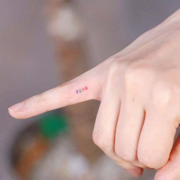 a person's finger with the word love tattooed on it, pointing to the left