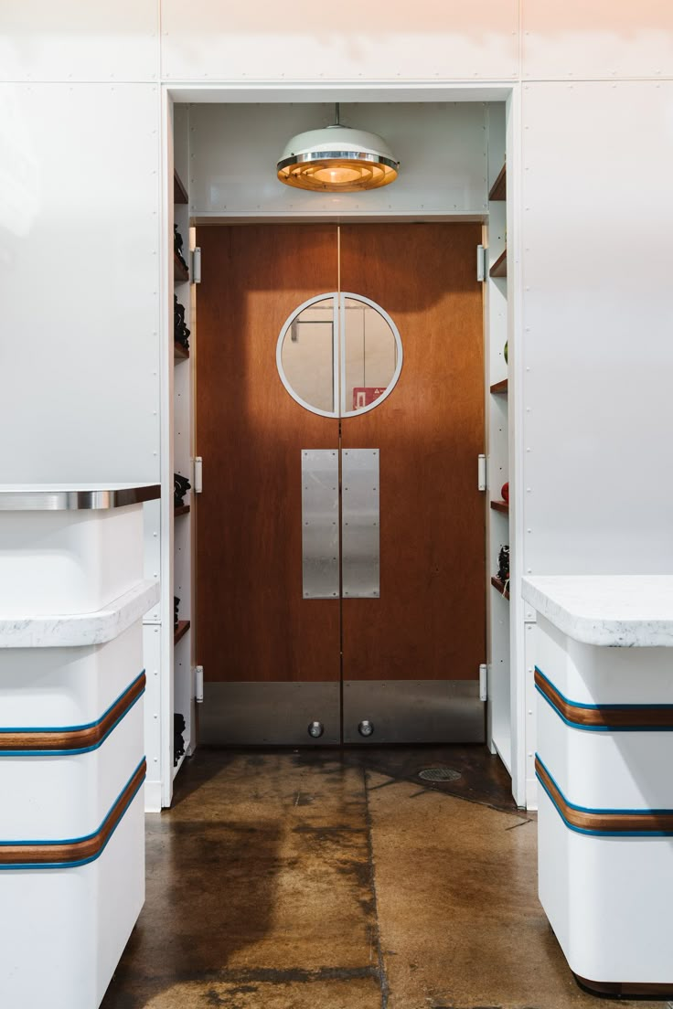 an open door leading into a kitchen with white cabinets and counter tops on both sides