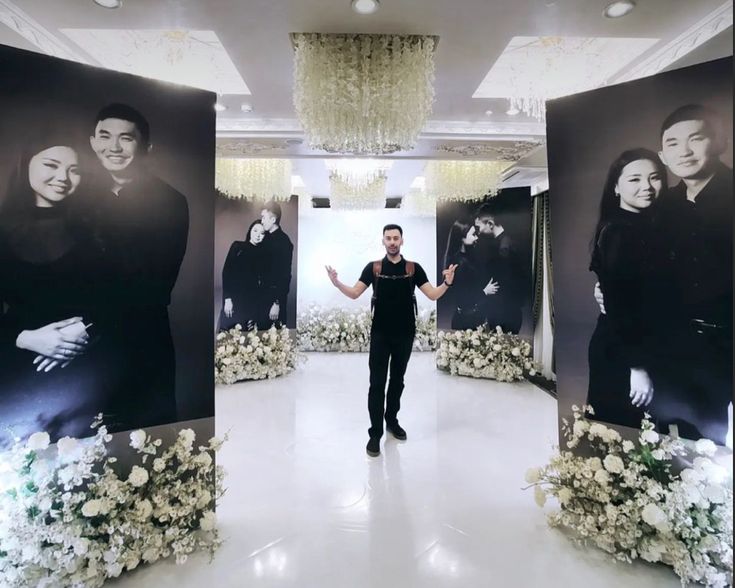 a man is standing in front of two large black and white pictures on the wall