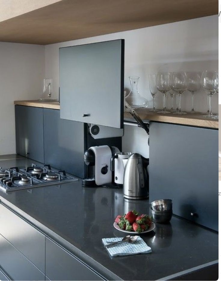 there is a coffee maker on the counter in this kitchen with wine glasses and strawberries