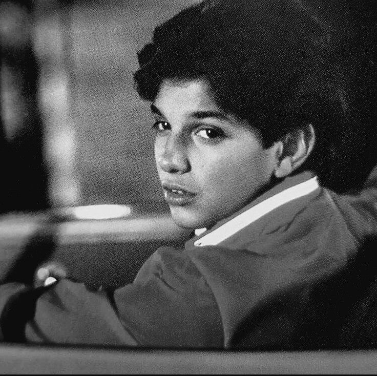 a black and white photo of a young man in a suit sitting at a desk