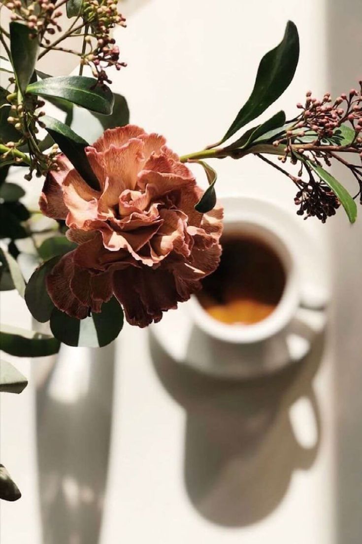 a cup of coffee and some flowers on a table