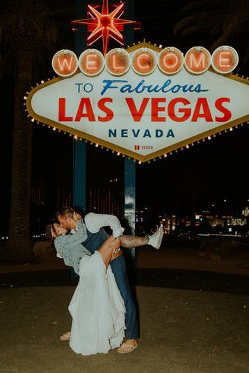 a bride and groom kissing in front of the welcome to fabulous las vegas sign at night