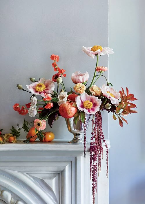 a vase filled with lots of flowers on top of a fireplace mantel next to a wall