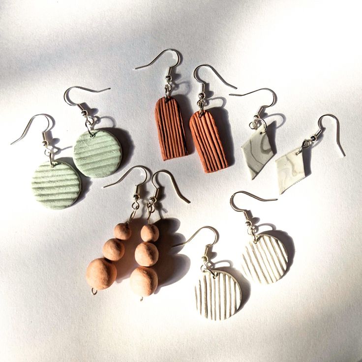 five different shaped wooden earrings sitting on top of a white table next to each other