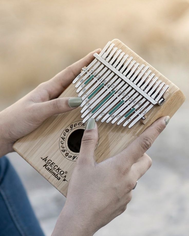 a woman is playing an xylons on a small wooden instrument with green strings