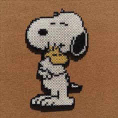 a cross stitch pattern of a snoopy dog with his paw in the air, on a brown background