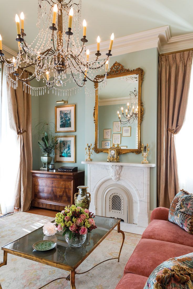 a living room filled with furniture and a chandelier hanging from the ceiling over a fire place