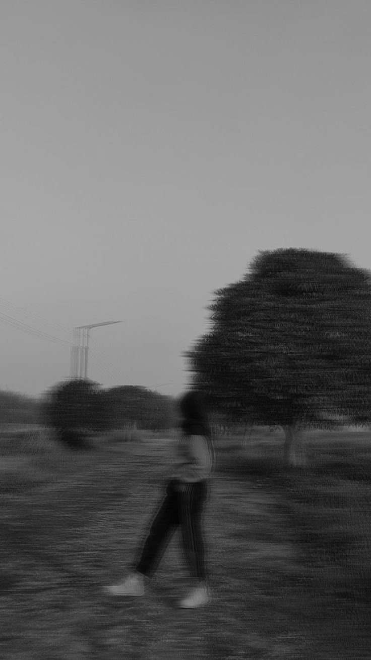 black and white photograph of person walking in field