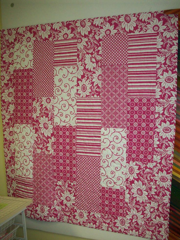 a pink and white quilt hanging on the wall