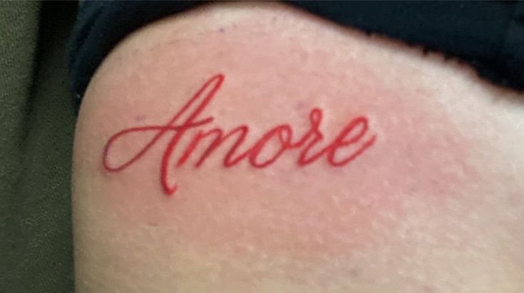 the word amore written in red ink on someone's lower back side thigh