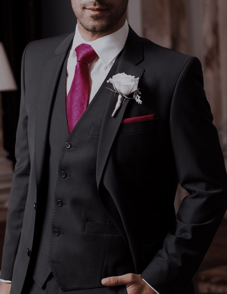 a man in a suit with a pink tie and white rose boutonniere