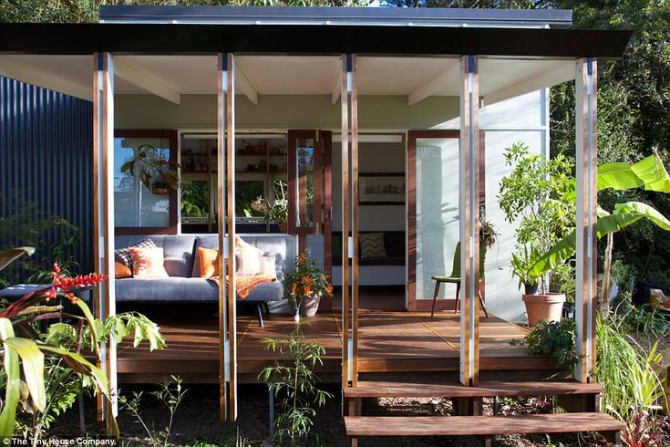 an outdoor living area with couches and potted plants in the foreground, surrounded by greenery