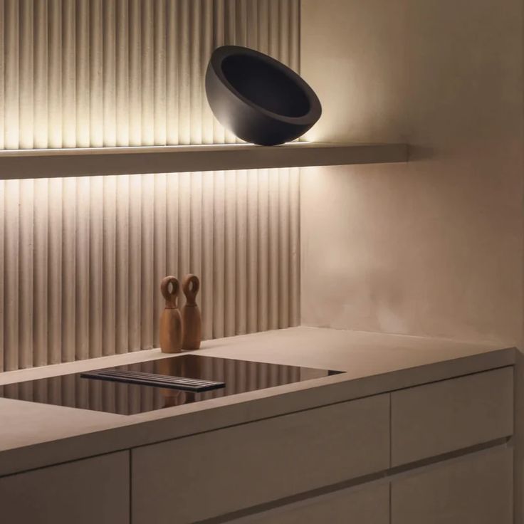 a modern kitchen with white counter tops and black lighting on the wall over the sink