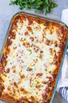 a casserole dish with meatballs and cheese in it on a blue towel