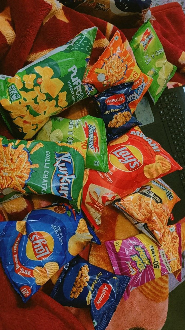 a pile of chips sitting on top of a red blanket next to a laptop computer