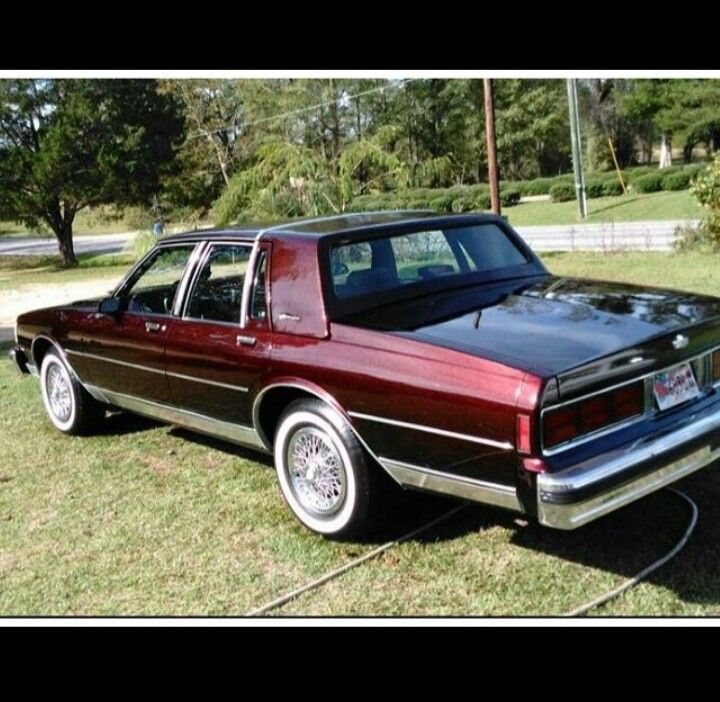 a red and black car parked on top of a grass covered field