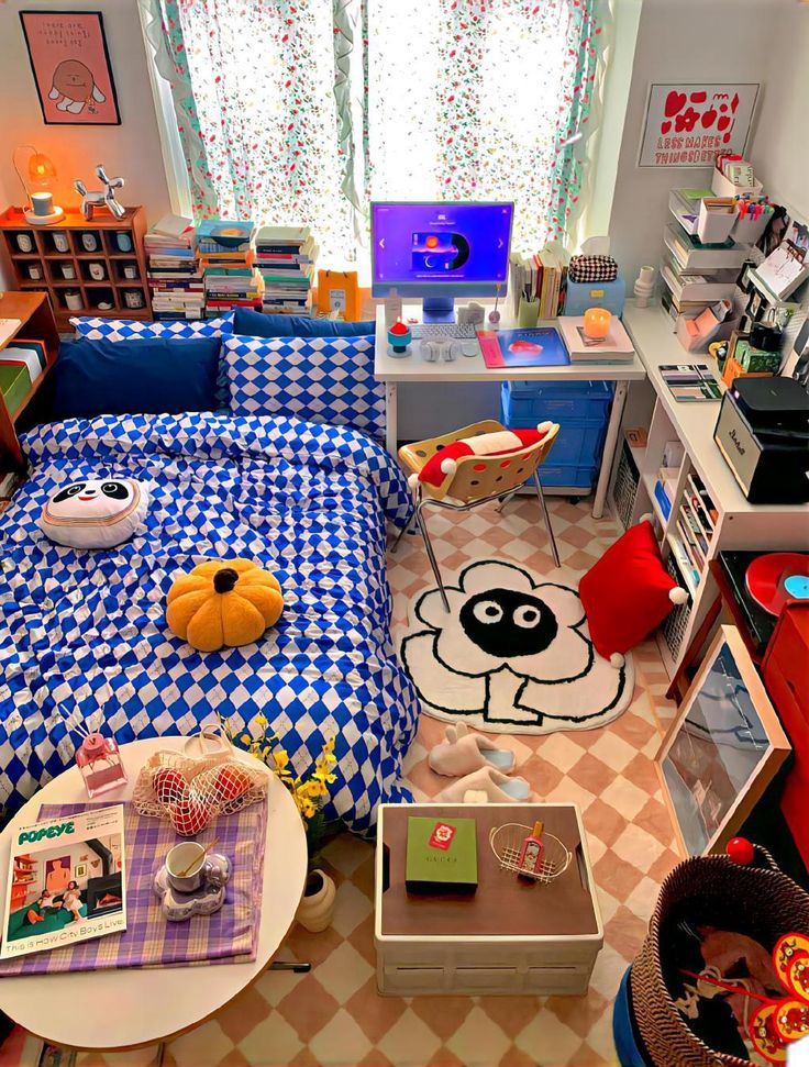 a bedroom with blue and white checkered bedspread on the floor, desks in the background