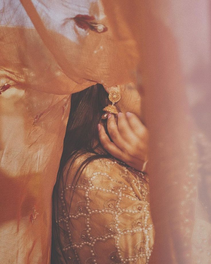 a woman standing under a sheer cloth covering her face