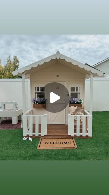 a small white house with a welcome mat on the grass in front of it that says welcome