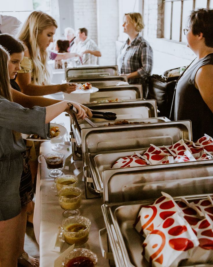 several people are serving themselves food from trays