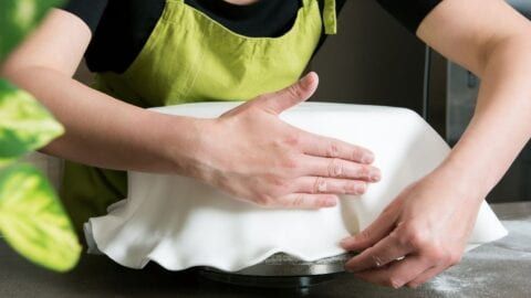 a woman in an apron is kneading dough on a pan with her hands