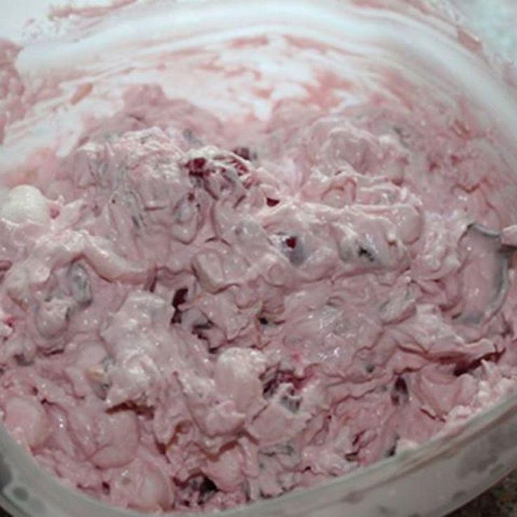 a bowl filled with ice cream sitting on top of a floor next to a red spoon