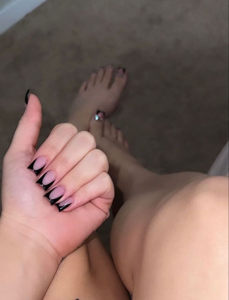 a woman's hand with black nail polish on it and her foot in the air