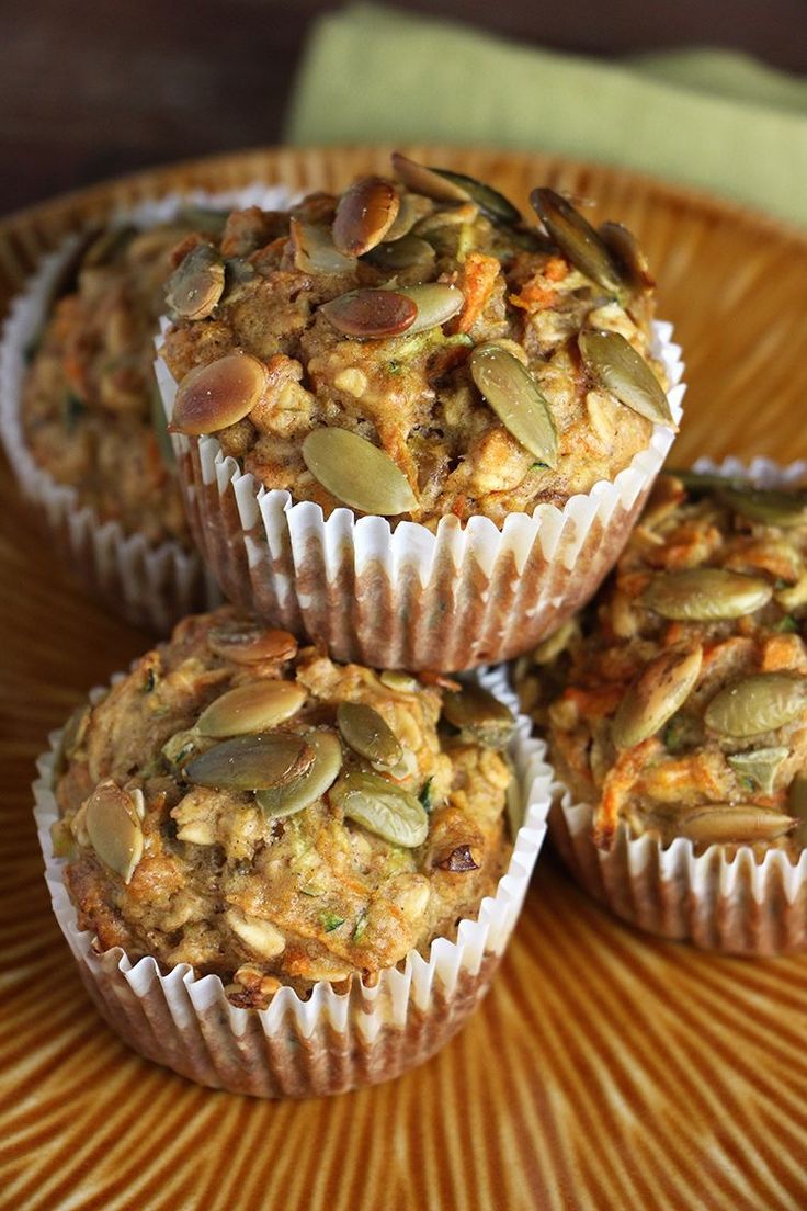 four muffins on a plate with pumpkin seeds in the top one is filled with nuts