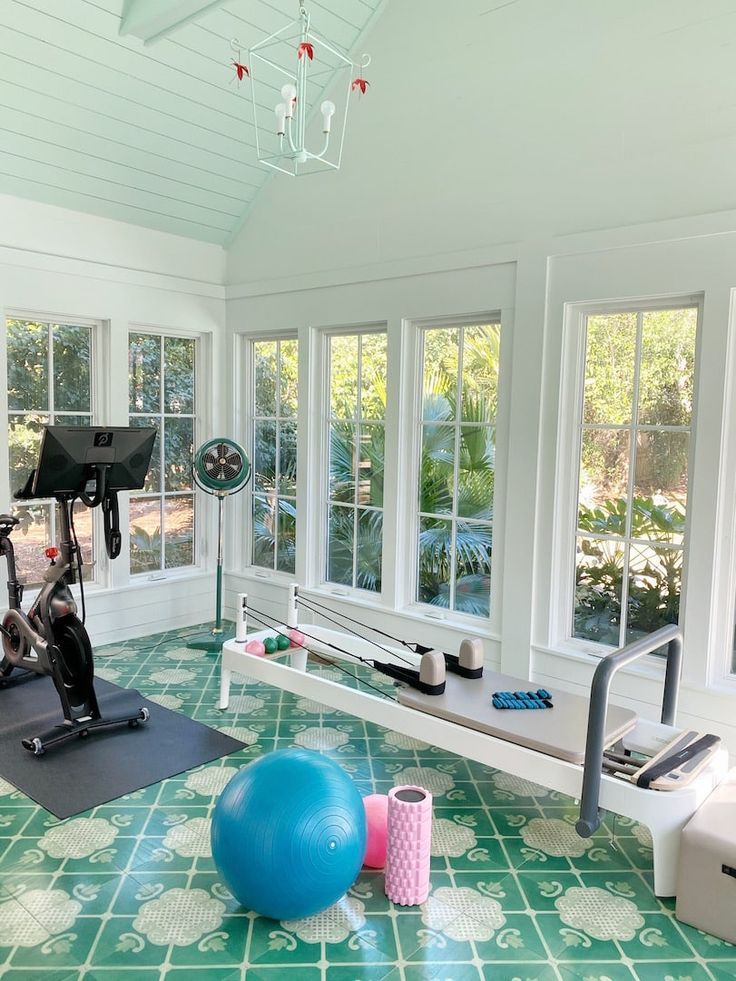 there is a gym room with exercise equipment in the center and windows on both sides