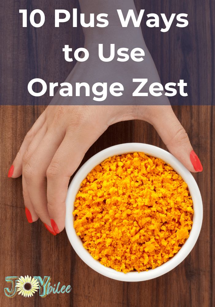 a woman's hands holding a bowl of orange zest on top of a wooden table